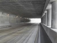 a city street is seen in a tunnel of an overpassing area with columns