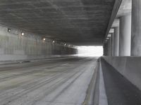 a city street is seen in a tunnel of an overpassing area with columns