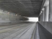 a city street is seen in a tunnel of an overpassing area with columns