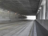 a city street is seen in a tunnel of an overpassing area with columns