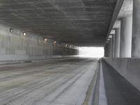 a city street is seen in a tunnel of an overpassing area with columns