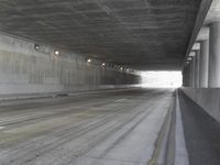 a city street is seen in a tunnel of an overpassing area with columns