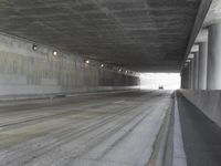 a city street is seen in a tunnel of an overpassing area with columns