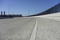 an empty freeway with two lanes with lights over the street and buildings behind it and two lanes on each side,