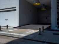 a gray walkway leading up to a building next to a yellow light lantern on top