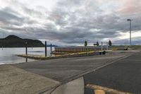 a paved path near a pier with a large body of water on one side and a mountain in the distance