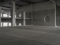 black and white photograph of a parking garage with a circular window near by windows on gray wall