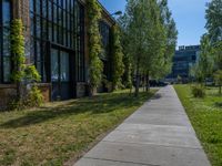 a sidewalk next to the brick building near trees in the park with lots of windows