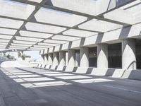 sun shines through the long shadows of concrete structures across an empty highway, underpass