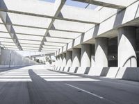 sun shines through the long shadows of concrete structures across an empty highway, underpass