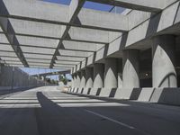 sun shines through the long shadows of concrete structures across an empty highway, underpass