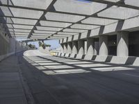 sun shines through the long shadows of concrete structures across an empty highway, underpass