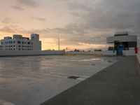 the roof has been damaged as sun sets over the parking lot in the foreground