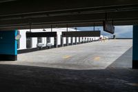 an empty building with some parking spaces in it's middleground, and cars parked nearby