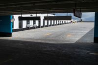 an empty building with some parking spaces in it's middleground, and cars parked nearby