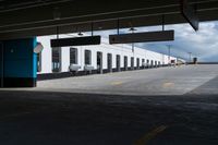 an empty building with some parking spaces in it's middleground, and cars parked nearby