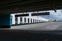 an empty building with some parking spaces in it's middleground, and cars parked nearby