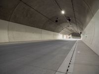 empty parking lane in concrete tunnel with light from inside view looking down floor area to right