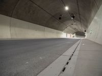 empty parking lane in concrete tunnel with light from inside view looking down floor area to right