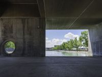 a concrete tunnel in the middle of a park with water running down it and trees around