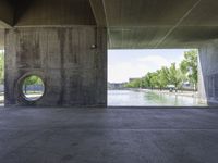 a concrete tunnel in the middle of a park with water running down it and trees around