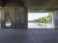 a concrete tunnel in the middle of a park with water running down it and trees around