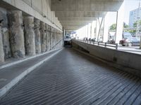 concrete walkway with cars and pedestrians on roadway area with bridge crossing overpass and elevated overpass