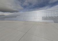 a concrete walkway on a cloudy day with a sky background in the distance and a wall covered with clouds