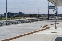 the walkway is concrete at the train station and beside the street is an empty parking space