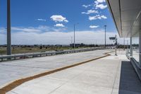 the walkway is concrete at the train station and beside the street is an empty parking space