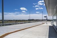 the walkway is concrete at the train station and beside the street is an empty parking space