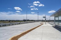 the walkway is concrete at the train station and beside the street is an empty parking space