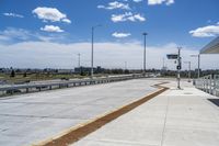 the walkway is concrete at the train station and beside the street is an empty parking space