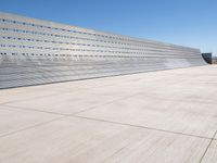 this is a concrete wall in a large building with many windows that are white and red