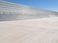 this is a concrete wall in a large building with many windows that are white and red