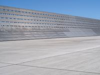 this is a concrete wall in a large building with many windows that are white and red