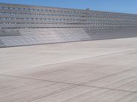 this is a concrete wall in a large building with many windows that are white and red