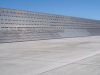 this is a concrete wall in a large building with many windows that are white and red