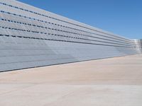 this is a concrete wall in a large building with many windows that are white and red