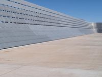 this is a concrete wall in a large building with many windows that are white and red