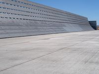 this is a concrete wall in a large building with many windows that are white and red