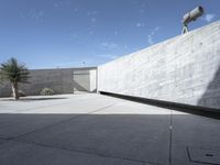 a cement wall and planters in an outdoor courtyard with a large concrete wall overlooking the sky