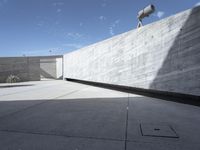 a cement wall and planters in an outdoor courtyard with a large concrete wall overlooking the sky