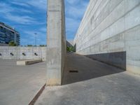 the empty parking lot in front of a wall with apartment buildings on it and a skateboarder on a ramp