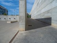 the empty parking lot in front of a wall with apartment buildings on it and a skateboarder on a ramp