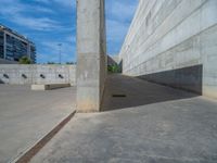 the empty parking lot in front of a wall with apartment buildings on it and a skateboarder on a ramp