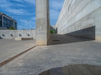 the empty parking lot in front of a wall with apartment buildings on it and a skateboarder on a ramp