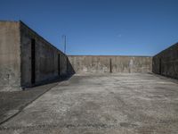 a parking area with cement walls and an entrance on one side of it, a sky in the background