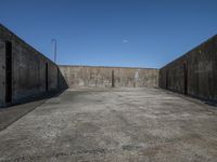 a parking area with cement walls and an entrance on one side of it, a sky in the background