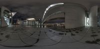 an exterior at night with reflective circular metal objects surrounding the walkway and walkways, and a cloudy sky above the roof